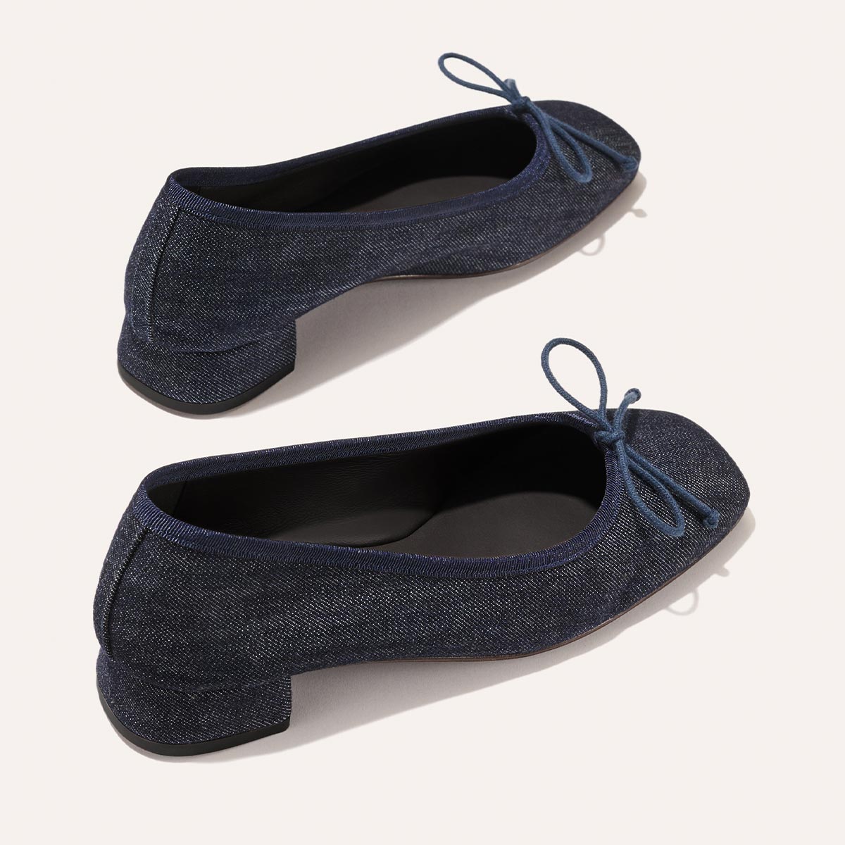 The Ada - Indigo Denim by margaux-development: classic dark blue denim ballet pumps with low heels, rounded toes, and matching bow accents, shown on a light background.
