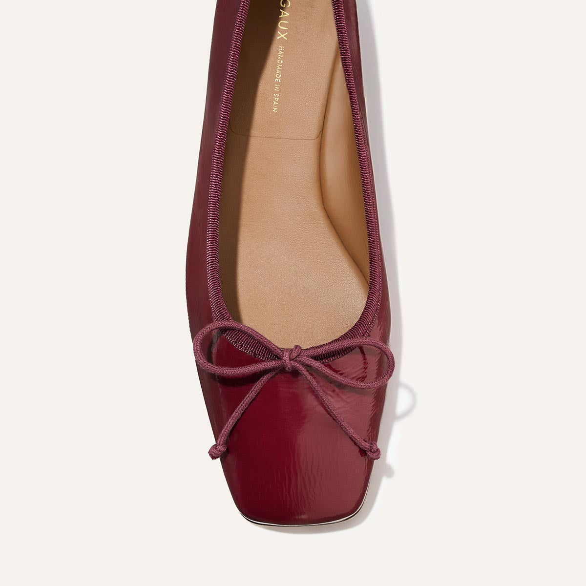 A top view of The Ada - Claret Crinkle Patent by margaux-development, a square-toe ballet flat in burgundy with a matching bow and cushioned insole for classic style and comfort.
