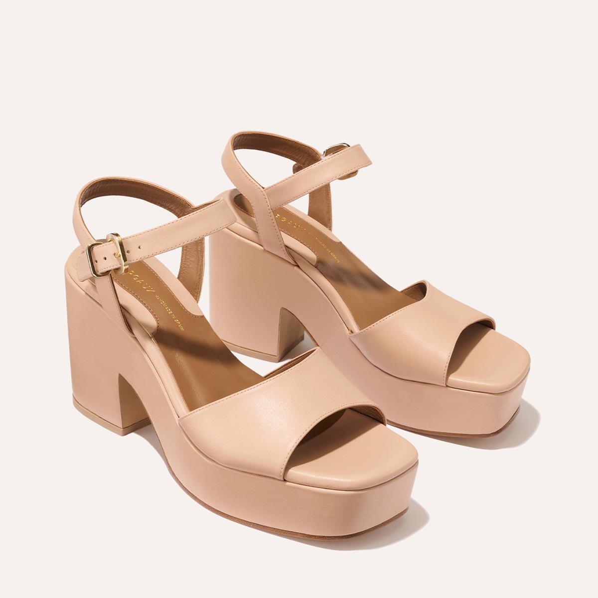 The Bardi - Petal Calf by margaux-development: nude-colored open-toe platform heel sandals with chunky high heels and ankle straps with gold-tone buckles, showcased on a plain light background for a modern yet glamorous look.