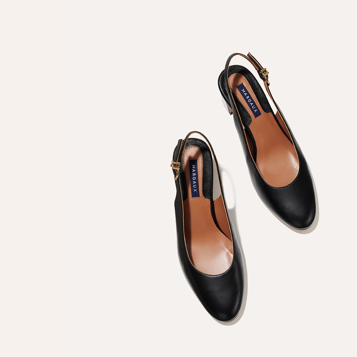 The Cluny Slingback in Black Nappa, featuring a sleek Italian nappa leather upper with an adjustable buckle and a comfortable 2.5-inch black heel.