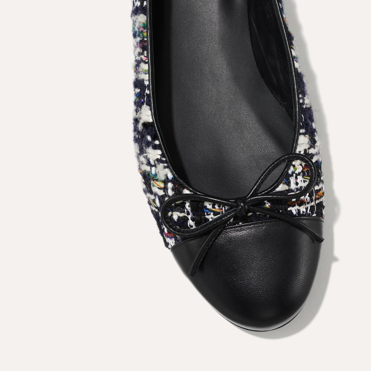 The Demi in Navy Tweed with a black cap-toe detail, a comfortable ballet flat with a rounded toe and adjustable cord bow detail.