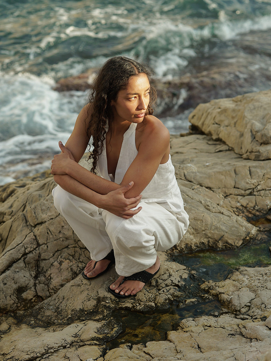 Woman wearing black woven thong sandals on a rocky beach