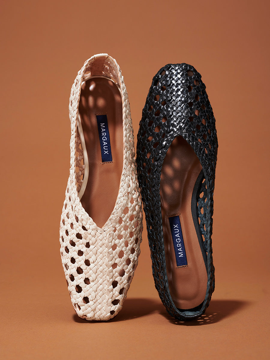 Two woven flats are displayed side by side on a brown background: one is beige and the other is black, both with Margaux labels on their insoles.