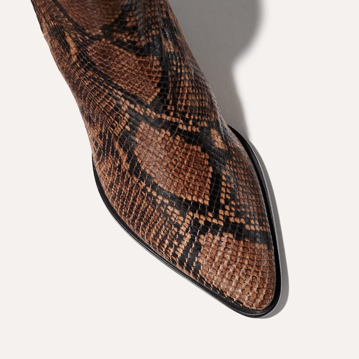 Close-up of Margaux’s The Downtown Boot First Edition in Espresso Python Embossed, featuring a brown snakeskin texture with black pattern detailing, shown from above on a light background.