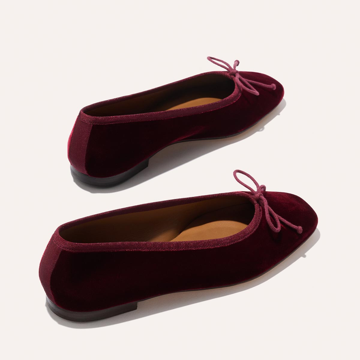 The Fonteyn - Burgundy Velvet by Margaux: handcrafted burgundy velvet ballet flats with small bows on the toes, displayed on a light background.