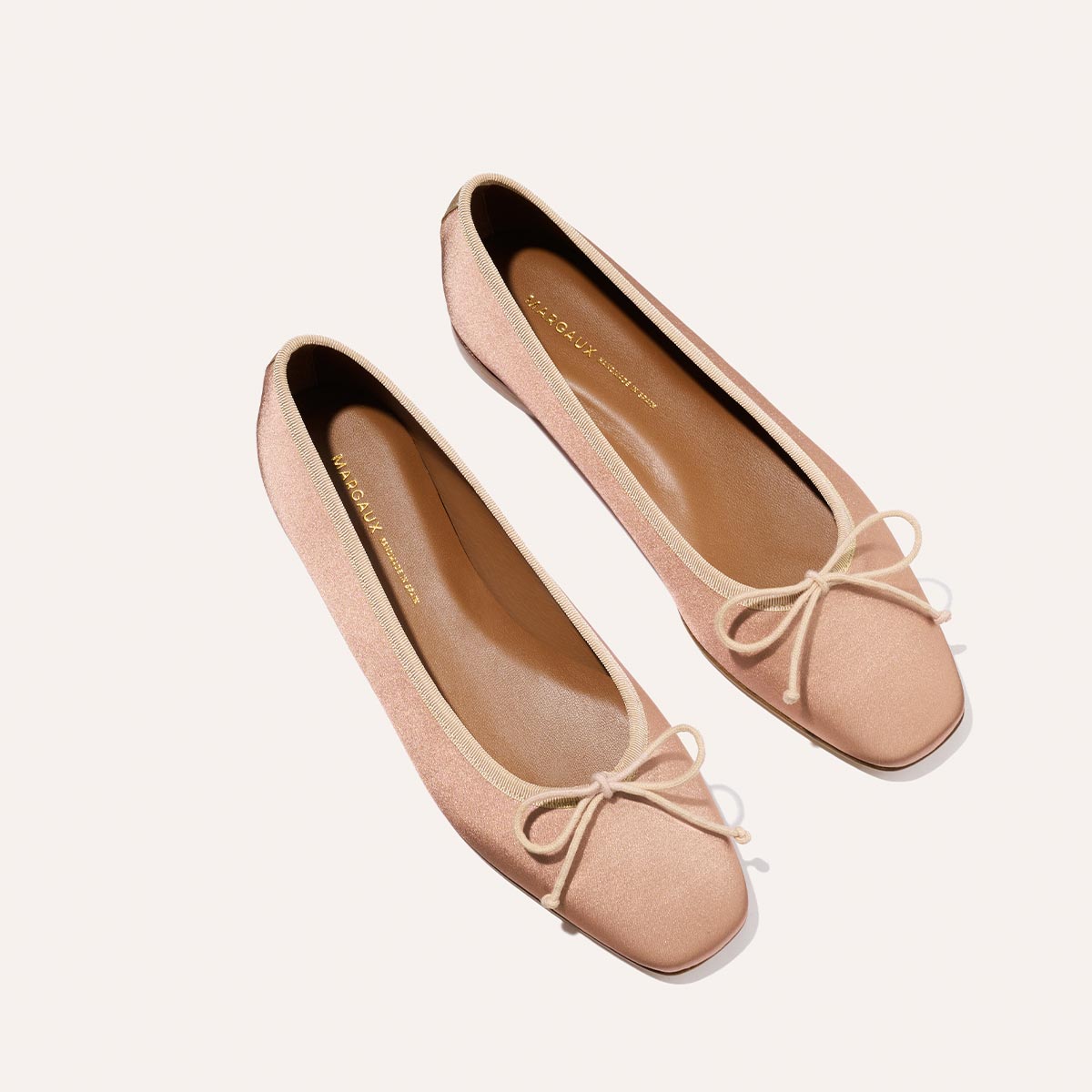 The Fonteyn - Dusty Pink Satin by Margaux: handcrafted ballet flats in light pink satin, featuring square toes and delicate bows for a comfort-first fit, displayed on a plain light background.