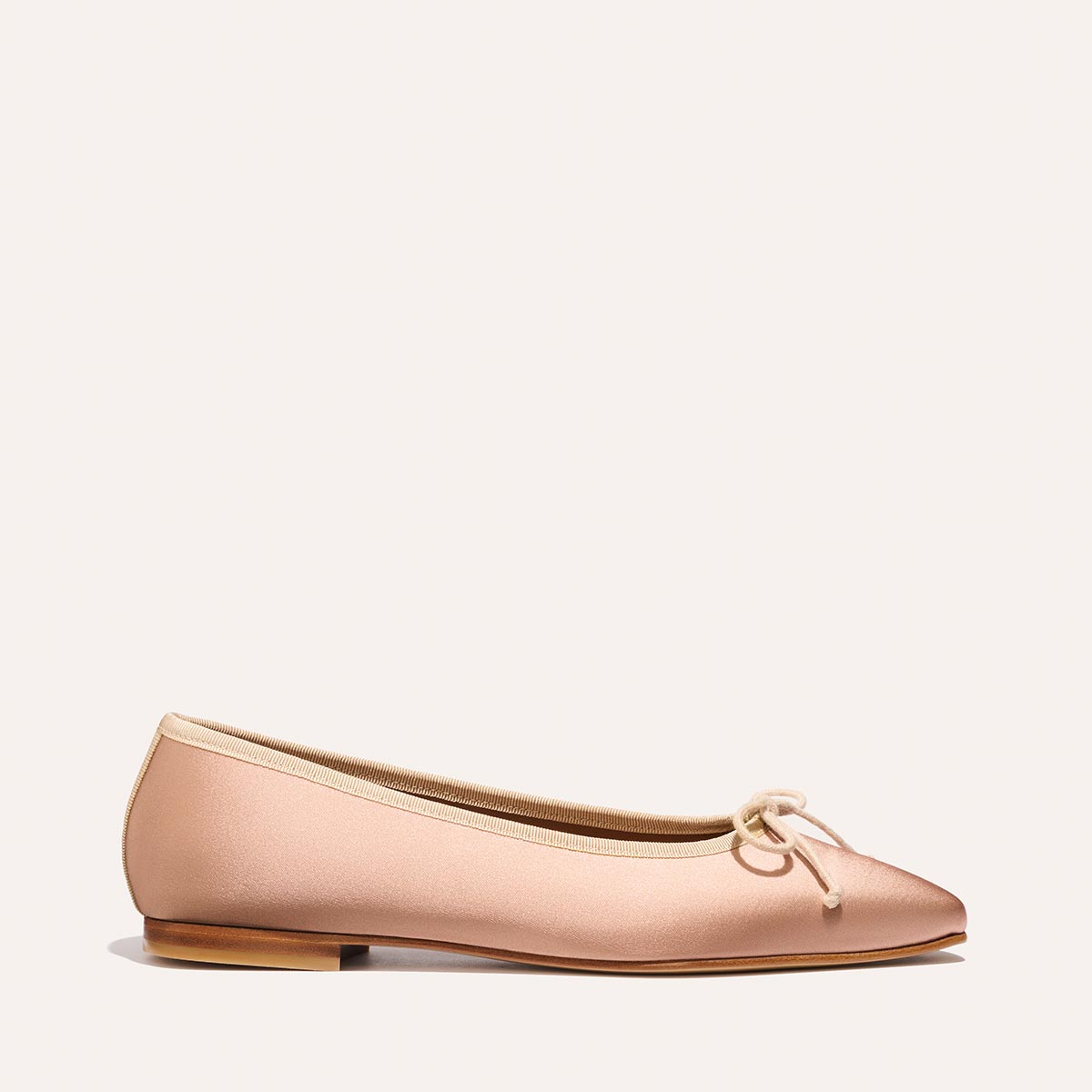 The Fonteyn - Dusty Pink Satin by Margaux: a comfort-first ballet flat with a rounded toe, small bow detail, and thin tan sole, shown in light pink satin against an off-white background.