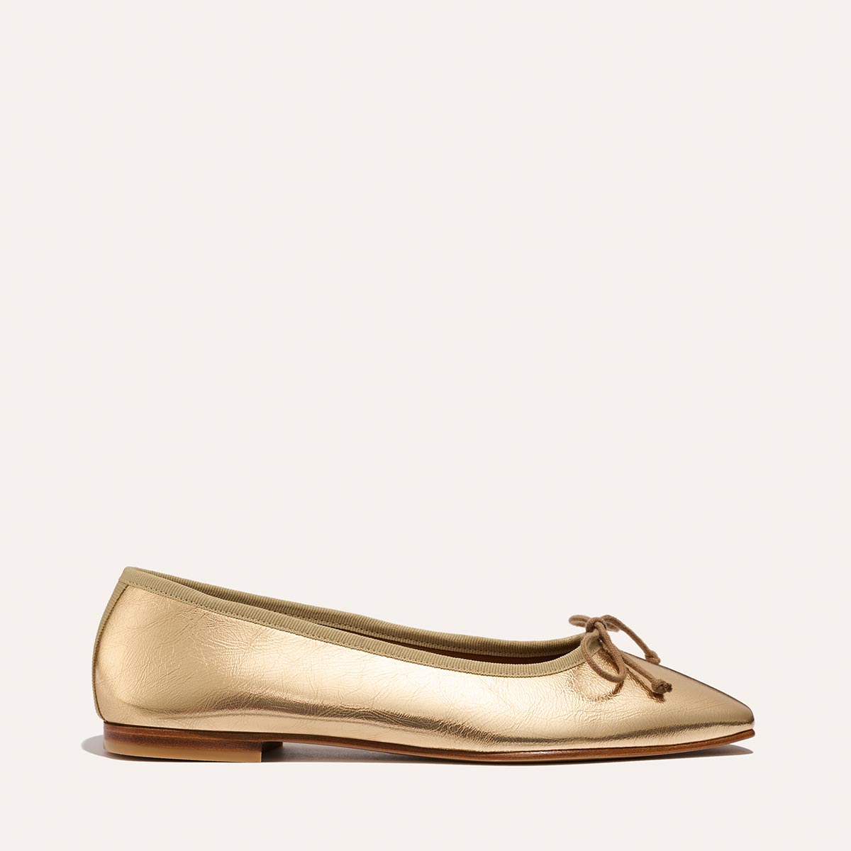 The Fonteyn - Gold Crinkle Nappa by Margaux is a gold pointed-toe ballet flat with a small bow, flat wooden sole, and textured finish, shown against a plain light background.