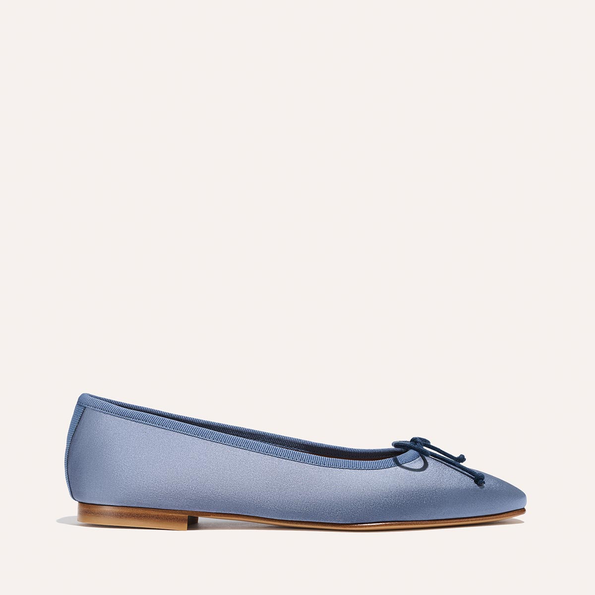 The Fonteyn - Slate Blue Satin by Margaux: a single blue ballet flat with a small bow on the rounded toe, low wooden heel, and a simple, elegant design, displayed on a plain light background.
