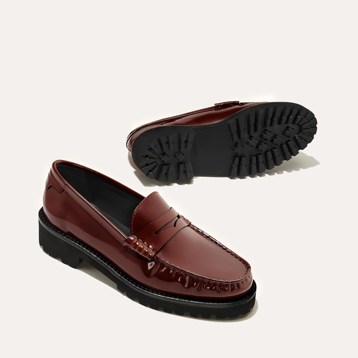 A pair of The Louisa Loafer First Edition - Hickory Calf by Margaux, with shiny hickory leather and black chunky soles: one shoe is upright showing the top and side, the other lies on its side to reveal the treaded lug sole.