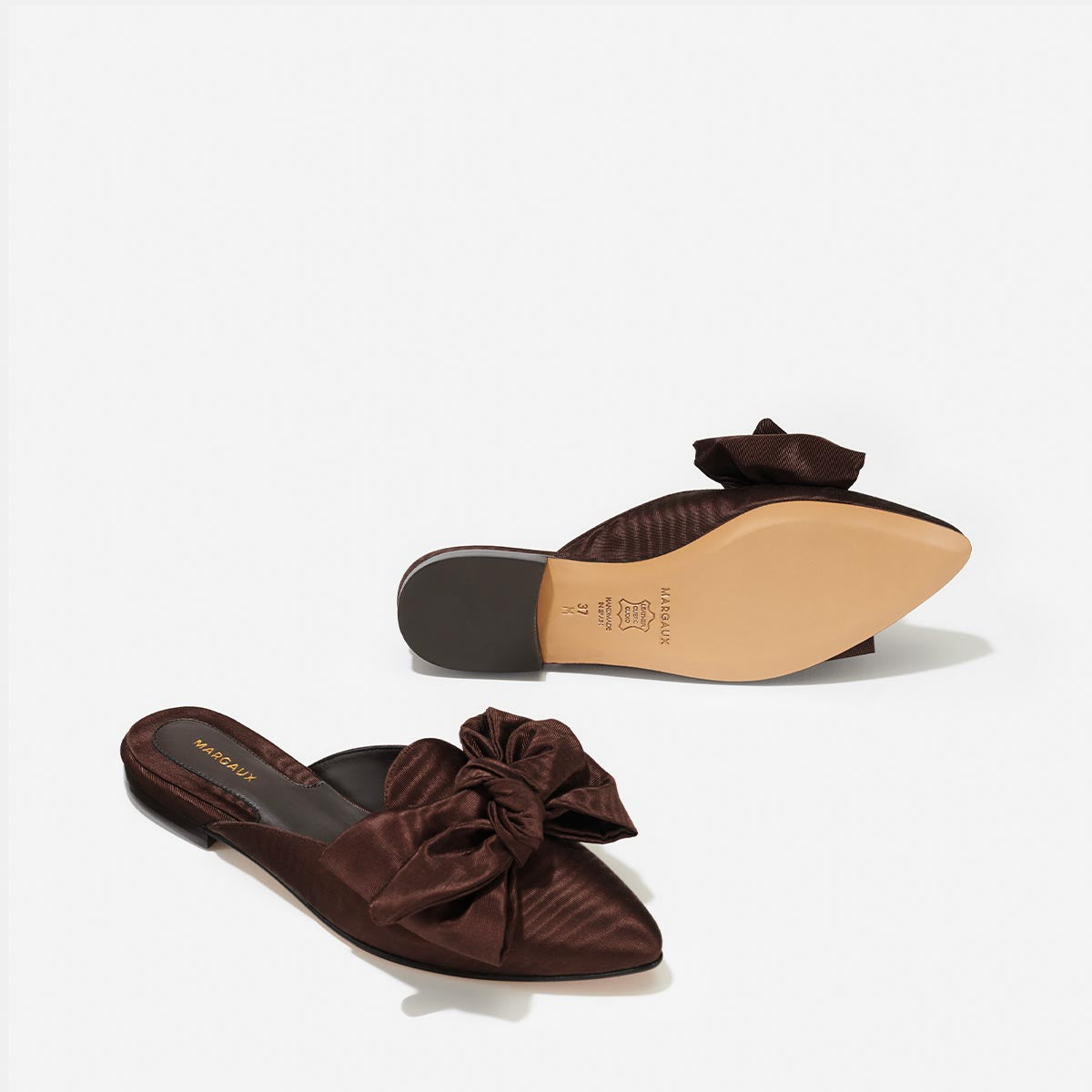 The Mule in Espresso Moire, a slip-on silhouette featuring a pointed toe and oversized bow detail.
