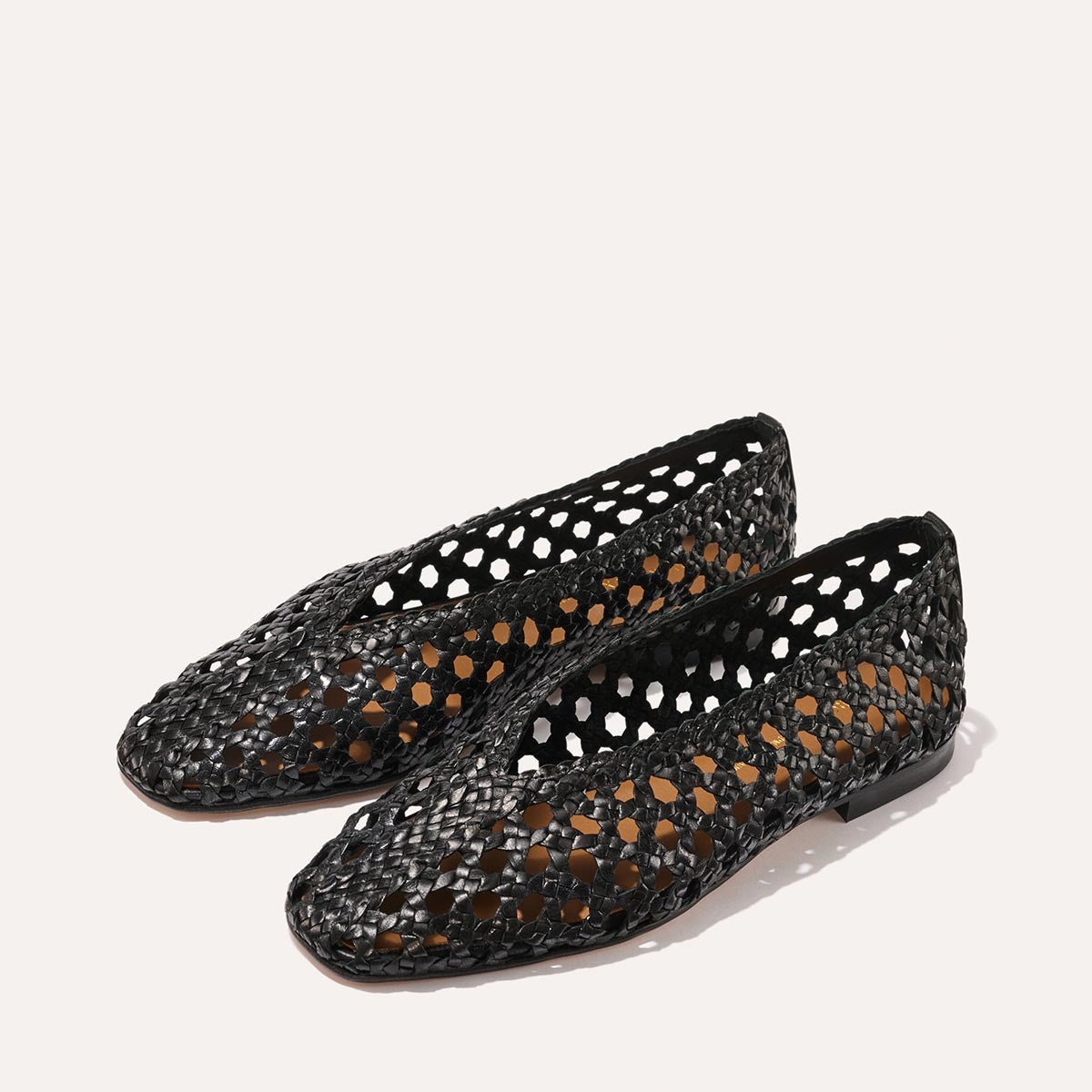 Two pairs of The Woven Paz - Black Leather flats by Margaux, featuring a honeycomb open design and higher rise, are displayed side by side on a light background.