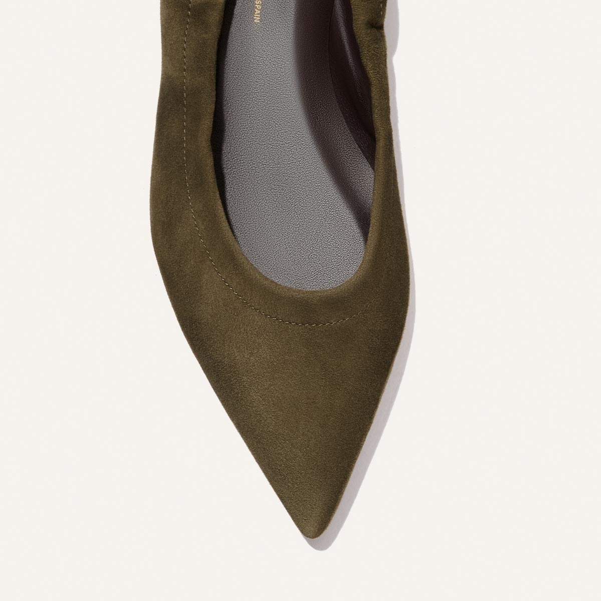 Close-up of the front part of The Roma - Moss Suede pointed-toe flat by Margaux on a light background.