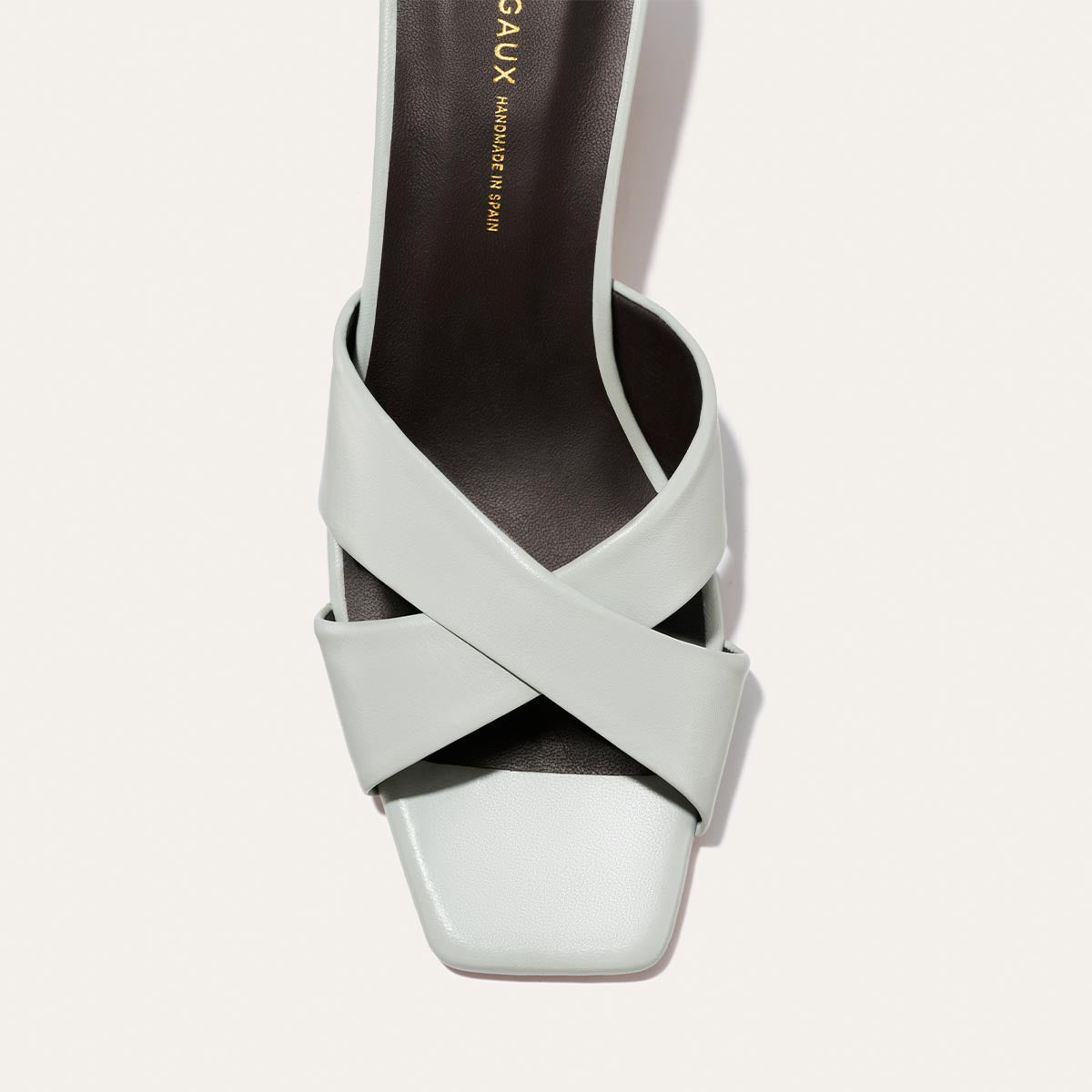 Light blue sandal with criss-cross straps on a light gray background