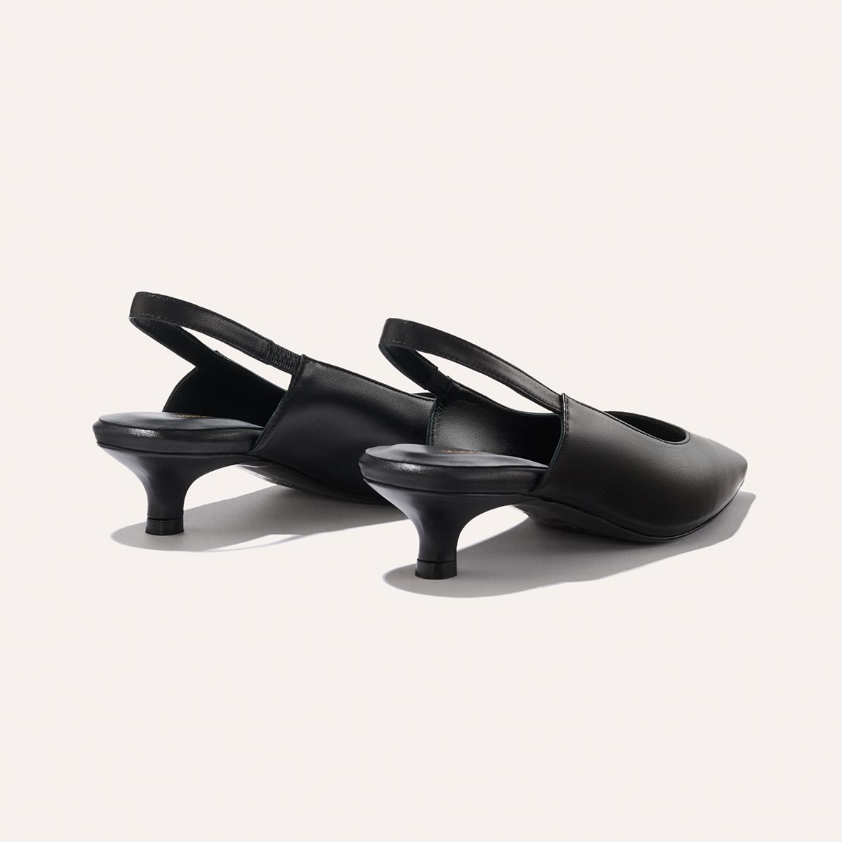 The Sofia Sling - Black Nappa by margaux-development: black pointed-toe slingback shoes with a micro heel and elastic heel band for support, displayed on a light background.