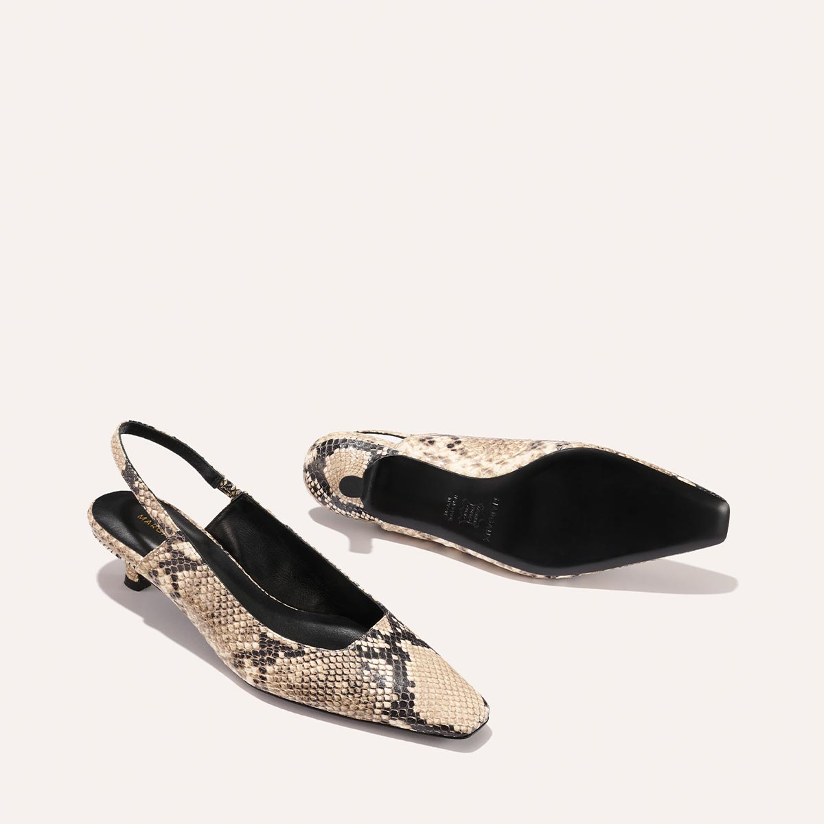 The Sofia Sling - Natural Python Embossed by Margaux features a beige and black snakeskin pattern, micro-heel, and snip nose. One shoe stands upright while the other lies on its side, revealing the sole, both set against a plain light background.