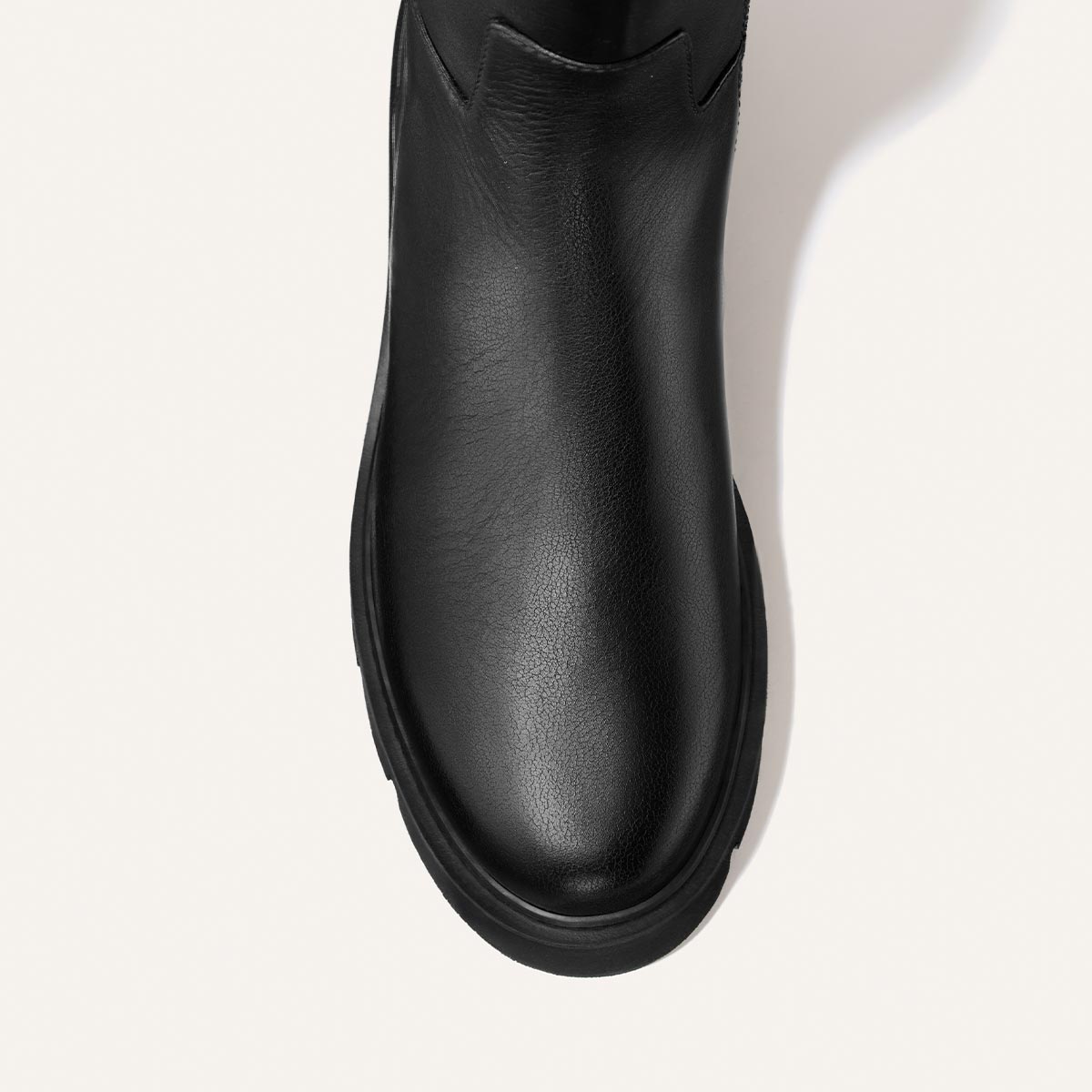 Top view of The Wells Boot - Black Calf by Margaux, featuring a rounded toe, visible sole, and smooth black leather texture, set against a plain, light background.
