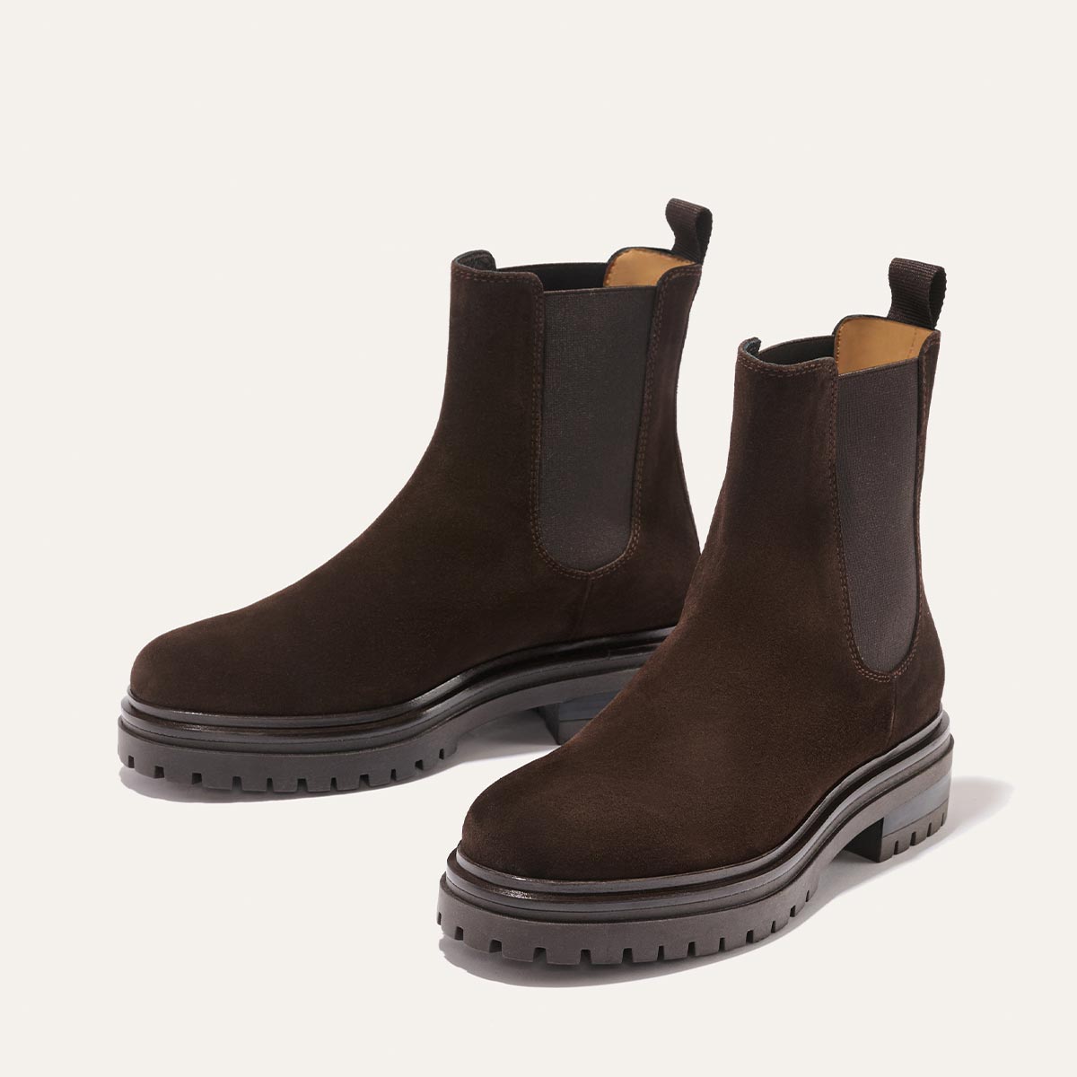 The West Chelsea Boot - Cocoa Suede by margaux-development: dark brown water-resistant suede boots with thick rubber lug soles, elastic side panels, and back pull tabs, shown on a light background.