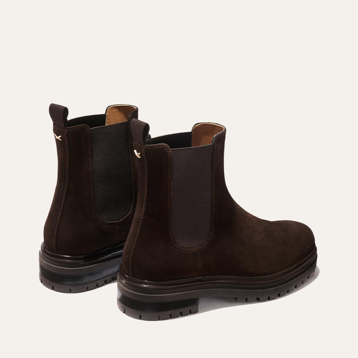 The West Chelsea Boot - Cocoa Suede by margaux-development features dark brown water-resistant suede, black elastic side panels, and thick black lug soles, displayed on a light background.