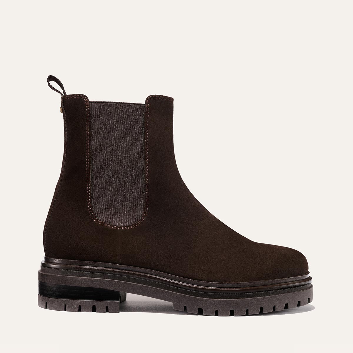 The West Chelsea Boot - Cocoa Suede by margaux-development is a dark brown, water-resistant suede Chelsea boot with a thick lug sole, elastic side panels, back pull tab, and a rounded toe, shown in profile against a light background.