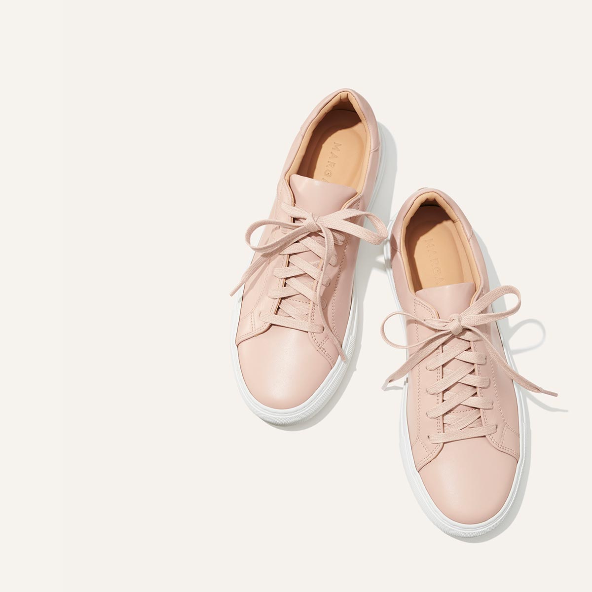 The Sneaker - Rose Calf by margaux-development: light pink leather sneakers with laces and white rubber soles, shown on a plain off-white background.