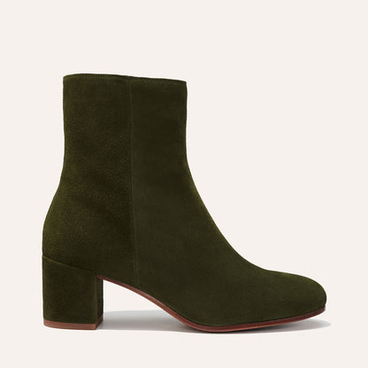 Margaux's The Boot in olive suede features an almond toe and chunky mid-heel, displayed from the side on a light background.