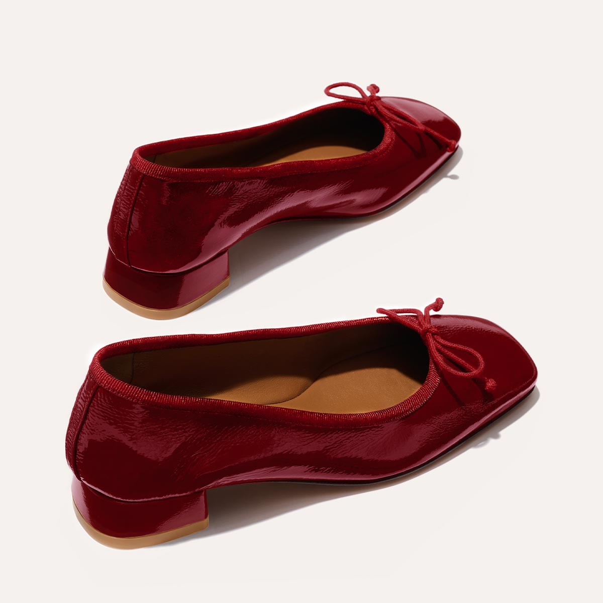 The Ada in Berry Crinkle Patent, a comfortable ballet flat with a square toe, adjustable cord bow detail, and comfortable 1-inch block heel.