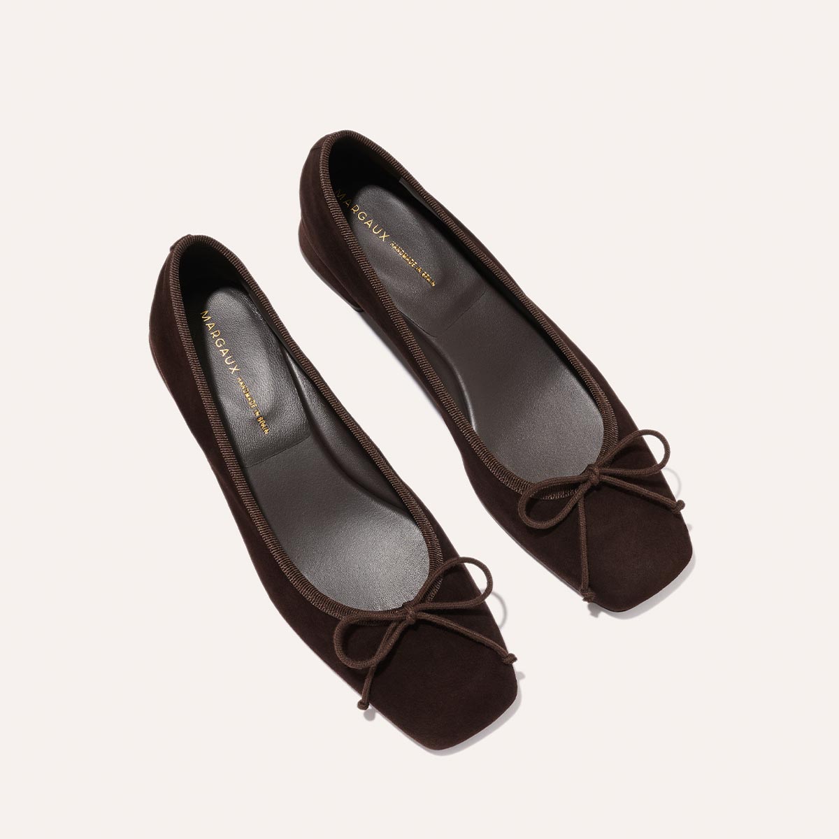The Ada - Espresso Suede by margaux-development: dark brown suede ballet flats with square toes, small matching bows, and sacchetto construction for a glove-like fit, displayed on a light background.