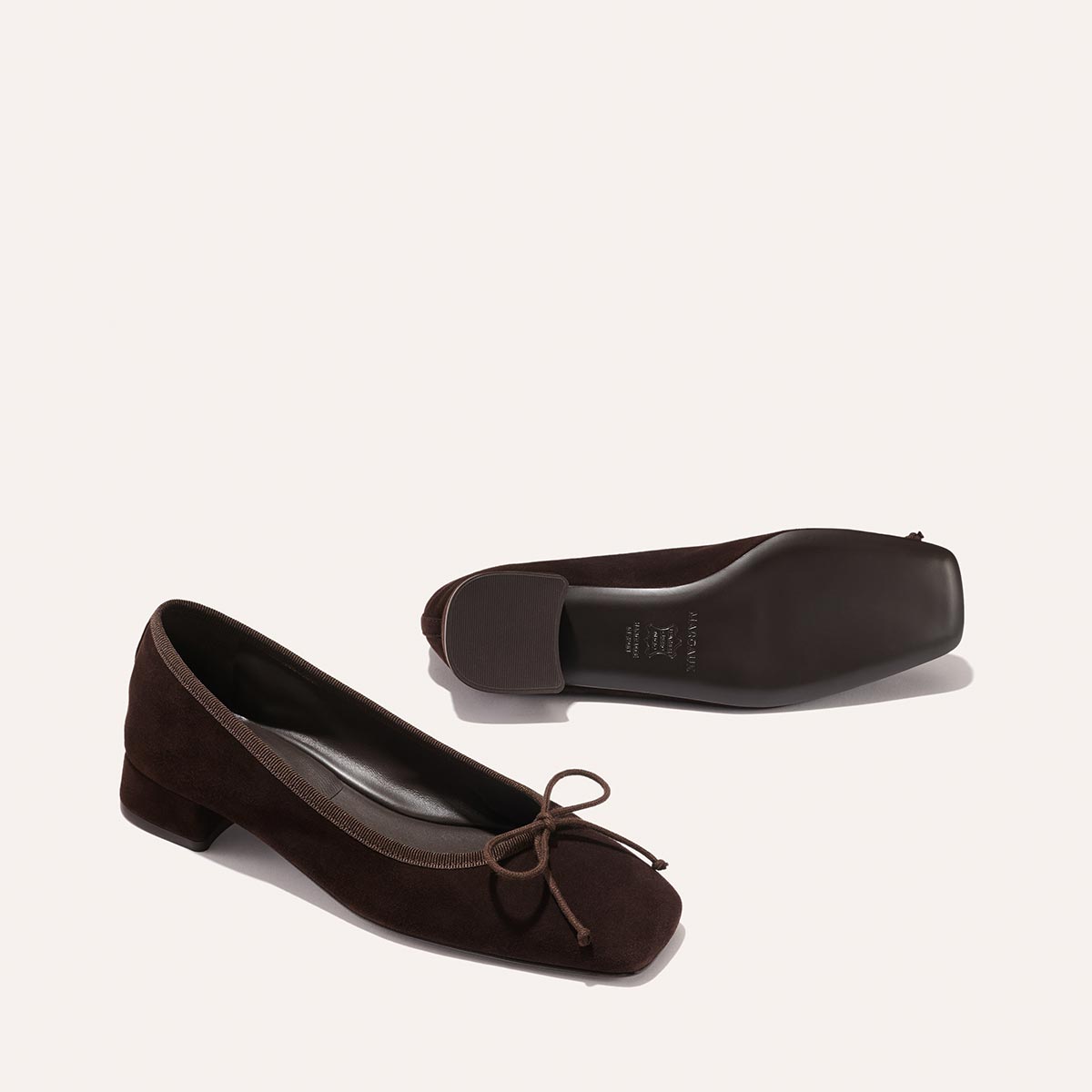 The Ada - Espresso Suede by margaux-development: low-heeled dark brown suede ballet pumps with bow details and sacchetto construction for a glove-like fit. Shown upright and on its side to display the sole, set against a light background.