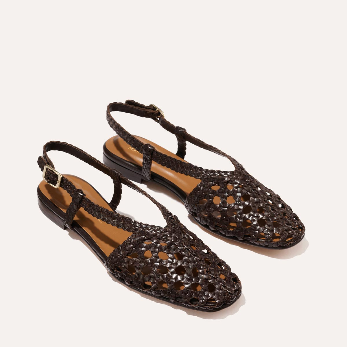 Margauxs The Altea - Espresso Woven Leather features closed toes, braided straps, and ankle buckles—stylish brown flat sandals ideal for summer—shown on a light background.