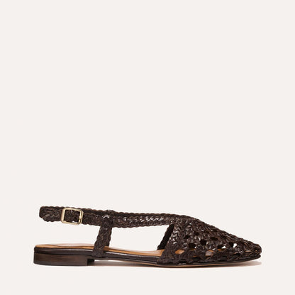 The Altea - Espresso Woven Leather by Margaux is a dark brown summer flat with a pointed toe, open sides, and an adjustable buckle strap, shown on a light background.