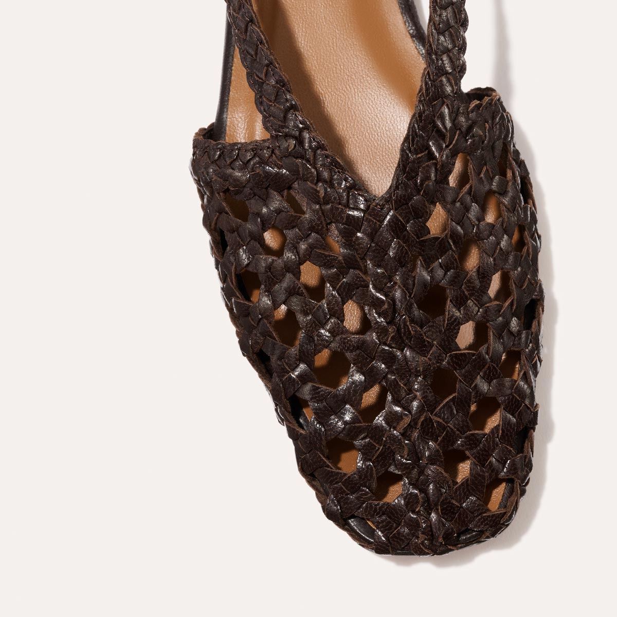 Close-up of Margaux’s The Altea - Espresso Woven Leather sandal, featuring a dark brown woven design with an open pattern and tan insole—perfect for keeping cool and stylish all summer.