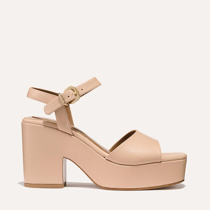 The Bardi - Petal Calf by margaux-development is a nude platform sandal featuring a chunky high heel, open toe, wide front strap, and an ankle strap with gold buckle, all highlighted on a plain light background.