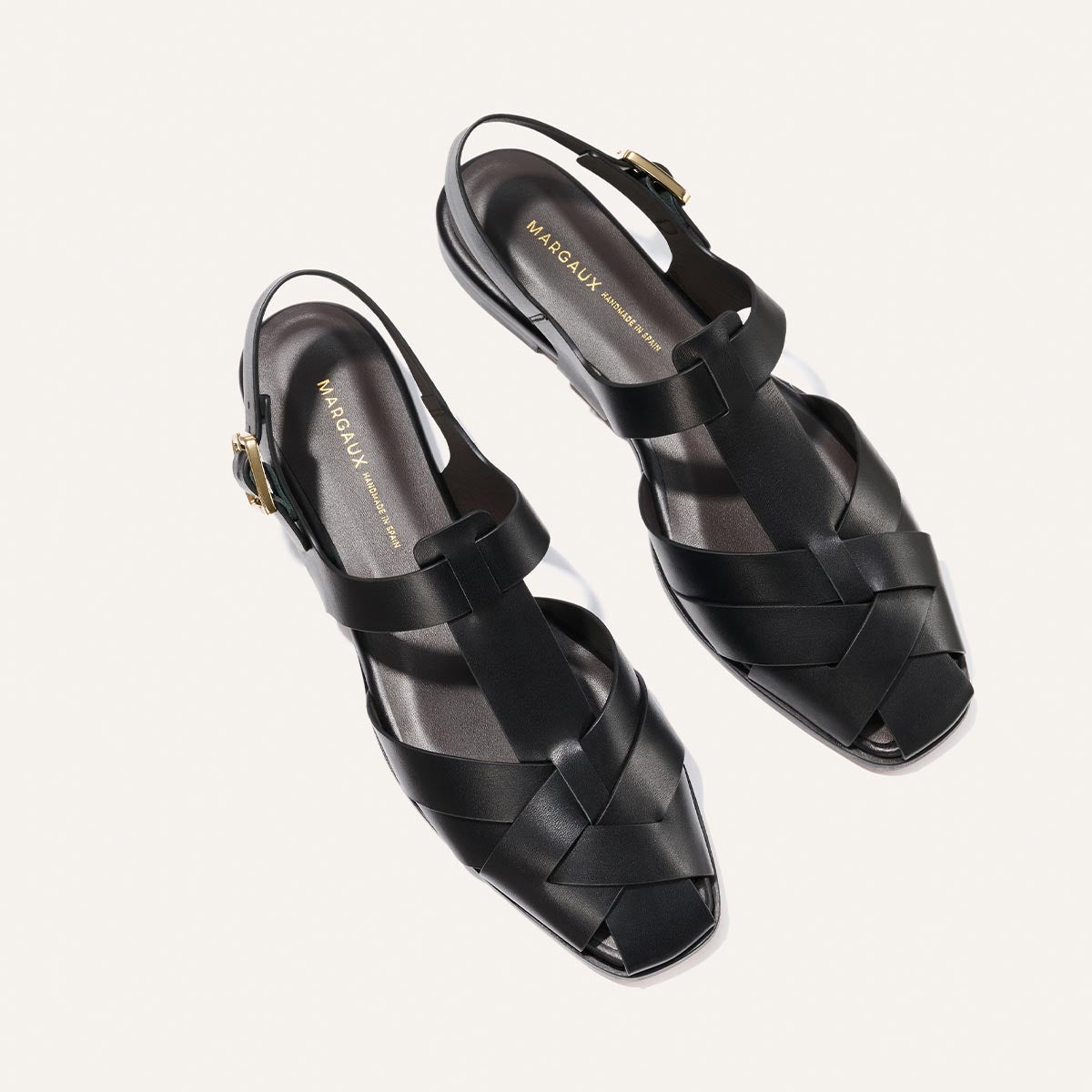 Black woven sandals with 'Margaux' branding on a white background