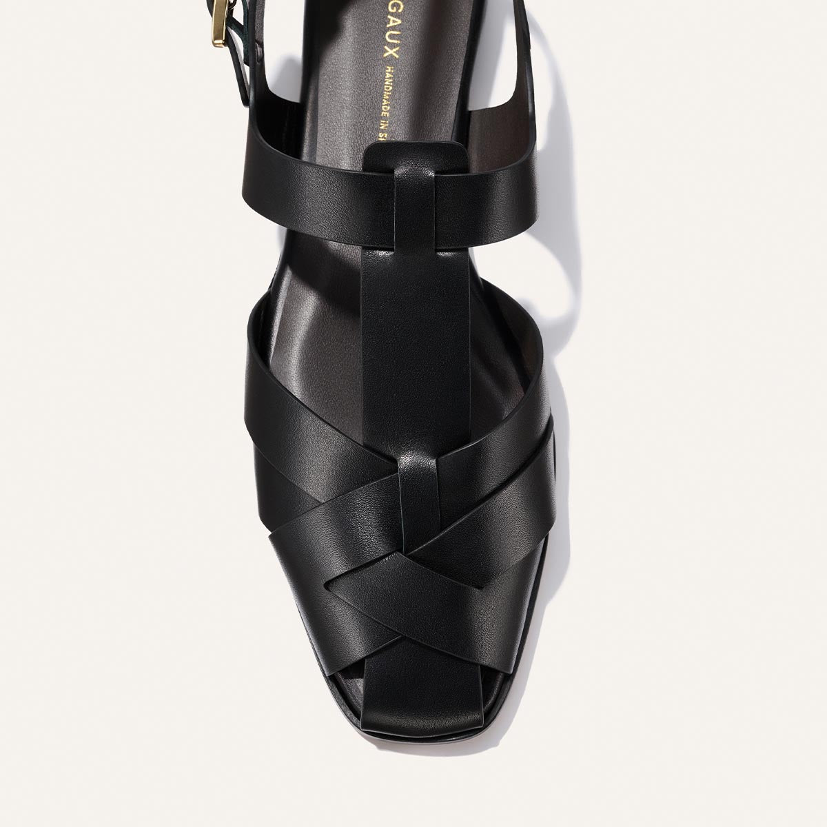 Black sandal with woven design on a white background