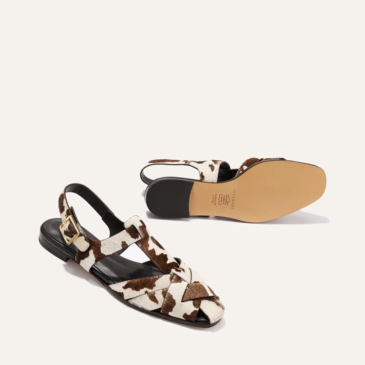 Cow print sandals on a white background