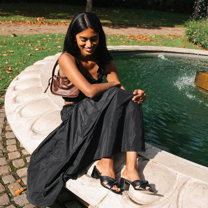 The Carmine Mule in Black Nappa, a slide-on heel featuring a plush knot detail and comfortable 2.5-inch block heel