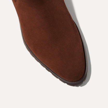 Close-up of the toe area of Margaux's The Chelsea Boot in Umber Suede, highlighting its smooth suede texture and dark brown sole against a light background.