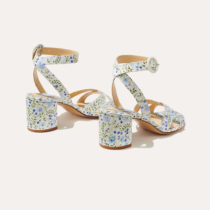 The City Sandal by margaux-development features ivory floral satin, chunky heels, ankle straps, an open-toe design, and a cushioned insole for comfort. Blue, green, and purple floral patterns add a vibrant touch.