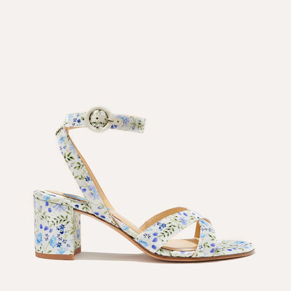 The City Sandal - Ivory Floral Satin by margaux-development features a single block heel, ankle strap with buckle, crossed toe straps, and cushioned insole, all in white satin with a blue and green floral pattern.