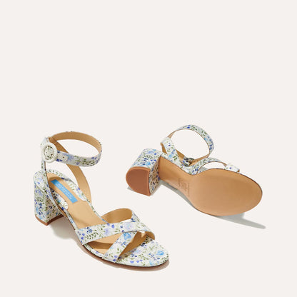 The City Sandal - Ivory Floral Satin by margaux-development features block heels, ankle straps with silver buckles, and a blue and purple floral print on white satin. A cushioned insole ensures comfort for all-day wear.
