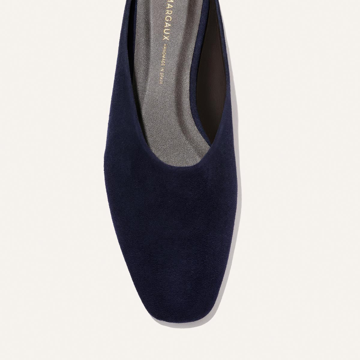 Top view of Margaux’s The Clara - Indigo Suede: a single navy blue suede flat with square toe, soft gray insole, and slipper-like silhouette—a versatile choice for all-day comfort.