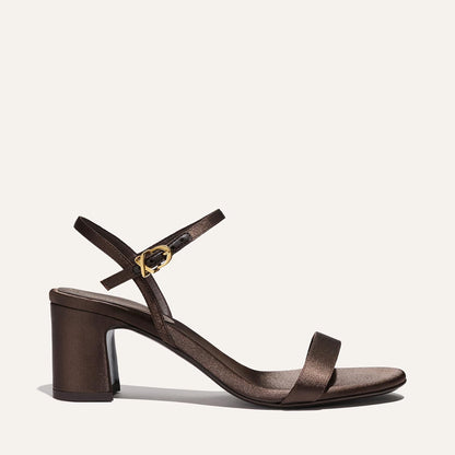 The Cleo Sandal - Espresso Satin by Margaux features a brown satin finish, open toe, block heel, slim toe strap, and an ankle strap with a gold buckle, shown against a plain light background.
