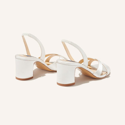 The Clotilde Sandal - Ivory Satin by margaux-development: white open-toe sandals with crisscross straps and block heels, shown on a neutral background.