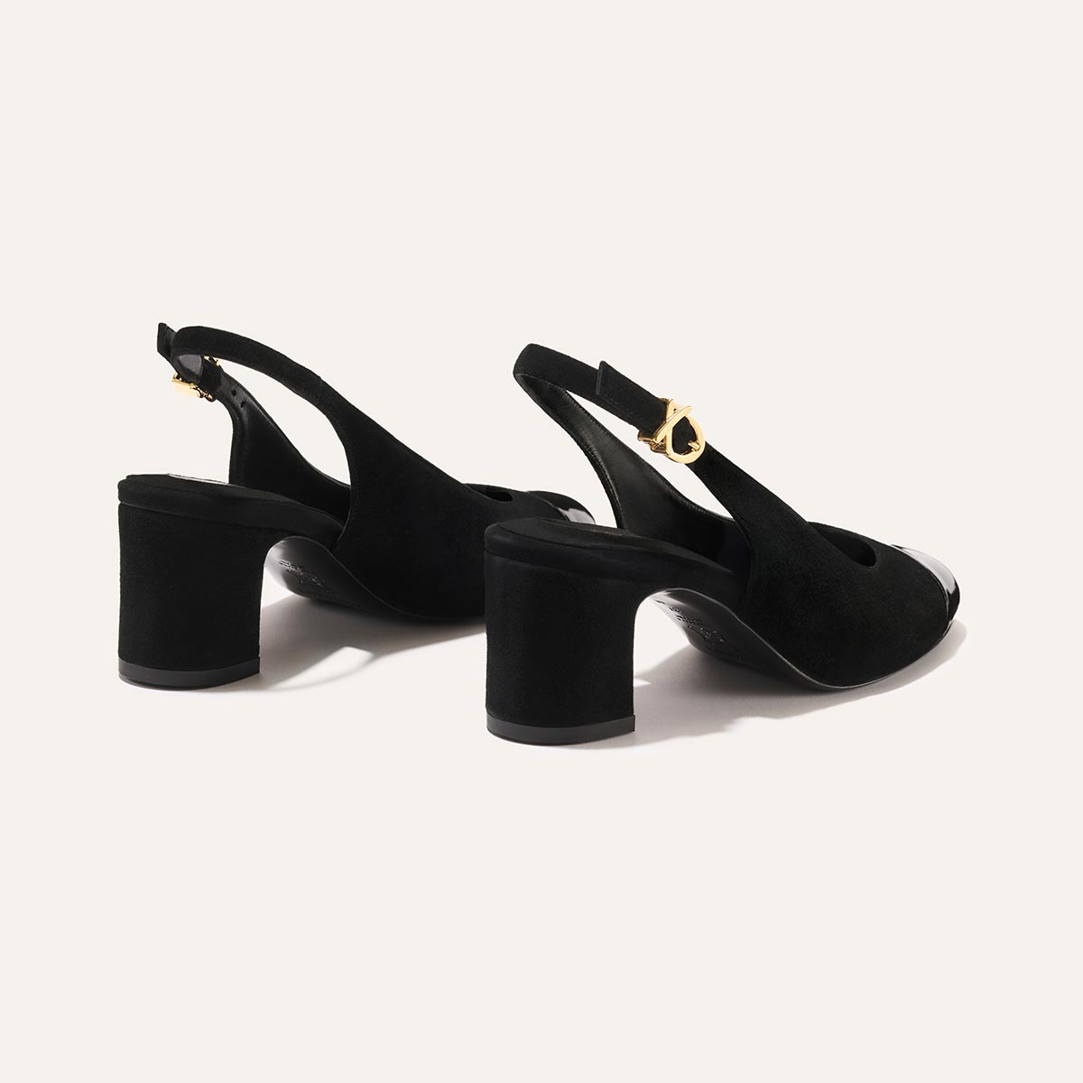 The Cluny Slingback by Margaux features black suede and patent, rounded toes, block heels, and gold buckle closures—an elegant choice for any occasion.