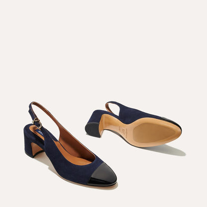 The Cluny Slingback in Navy Suede, featuring a sleek patent captoe detail with an adjustable buckle and a comfortable 2.5-inch black heel. 