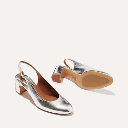 The Cluny Slingback in shiny Silver Crinkle Nappa, featuring a sleek Italian nappa leather upper with an adjustable buckle and a comfortable 2.5-inch black heel.