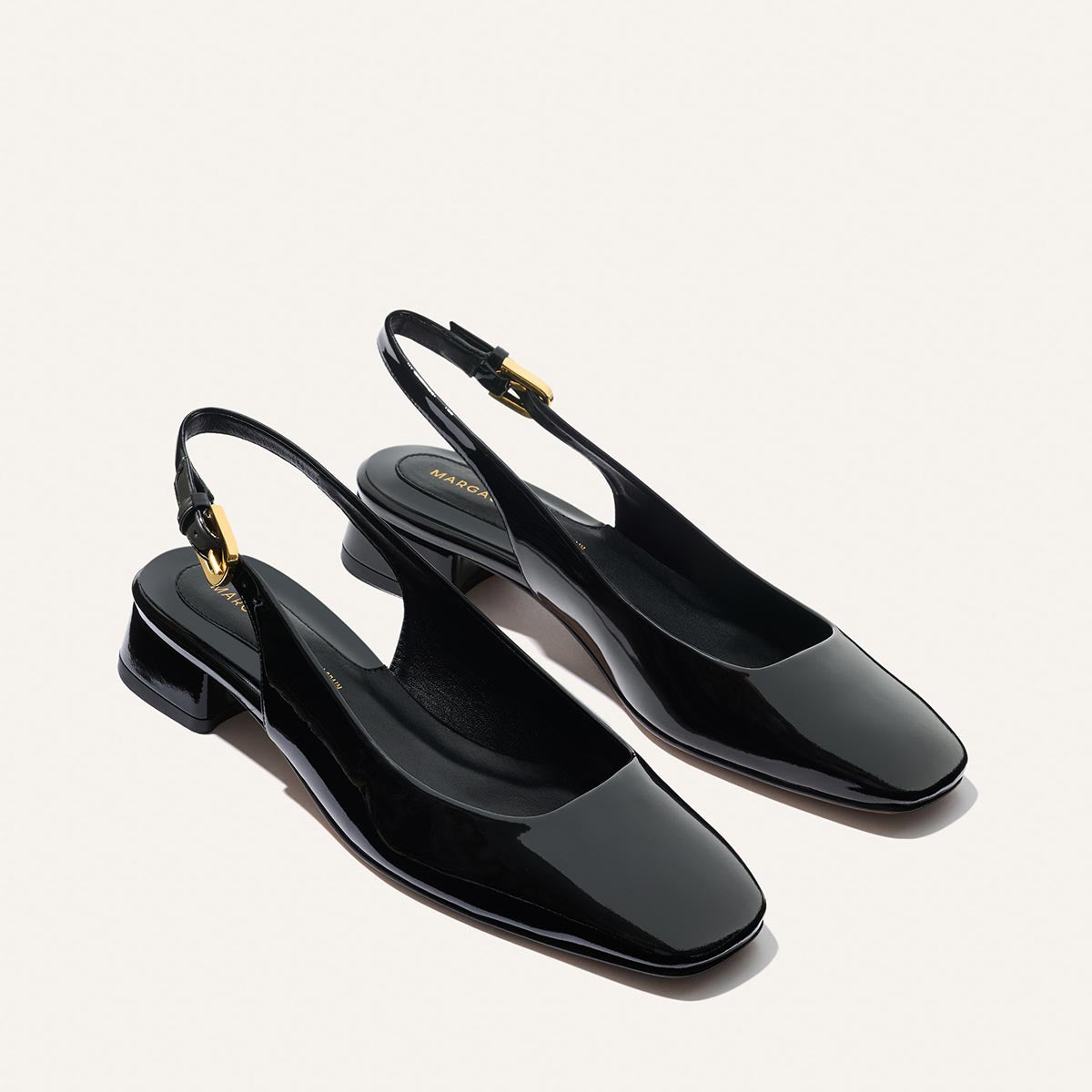 The Darcy Slingback - Black Patent by Margaux features a glossy black finish, low block heel, square toe, gold buckle accents, and adjustable slingback strap—ideal for warm-weather days. Shown on a light background.