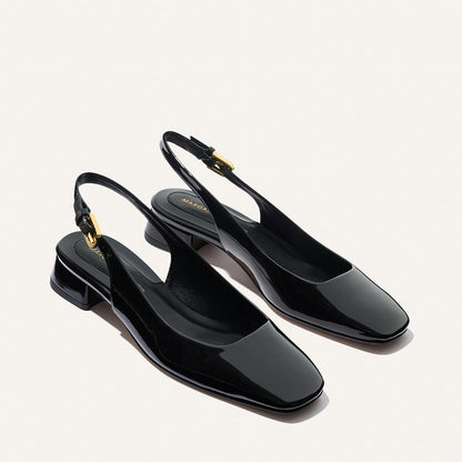 The Darcy Slingback - Black Patent by Margaux features a glossy black finish, low block heel, square toe, gold buckle accents, and adjustable slingback strap—ideal for warm-weather days. Shown on a light background.