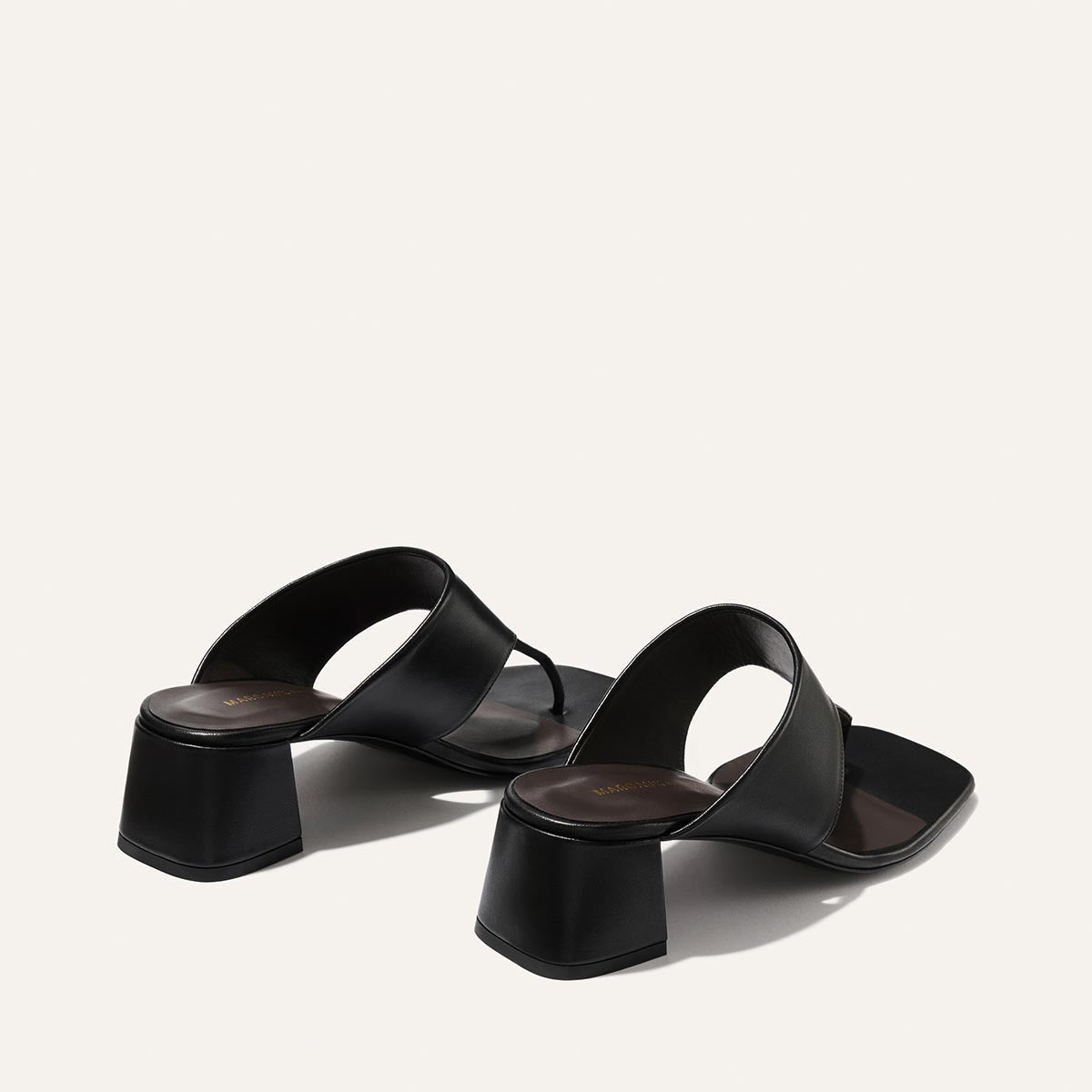 Black high-heeled sandals on a light gray background
